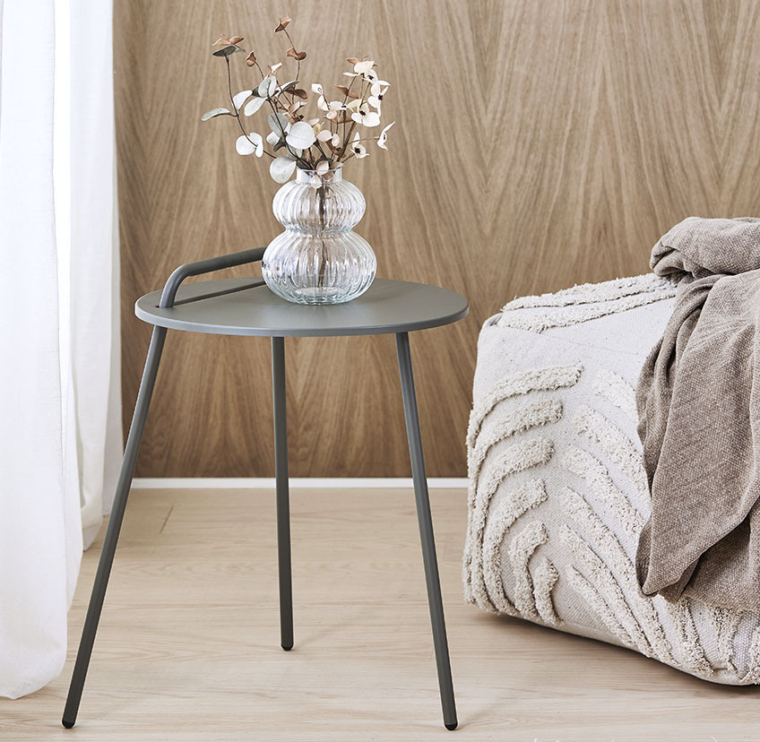 Mesa de apoio minimalista com três pernas e pega e pufe bege claro com superfície suave e estampada 