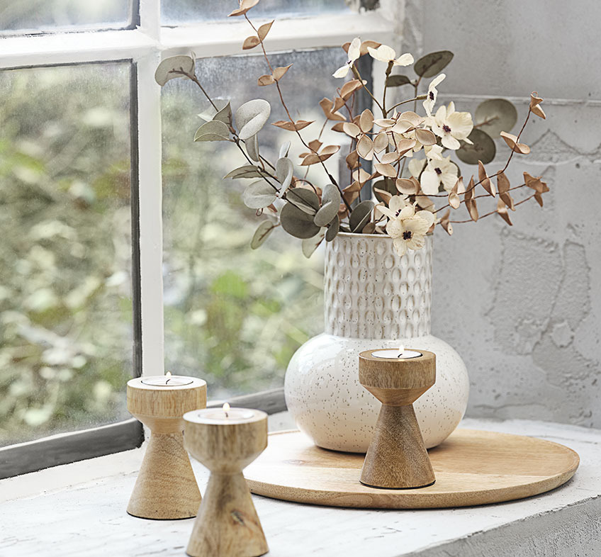 Vaso bege claro ou branco em relevo com flores artificiais e suportes para velas de madeira 