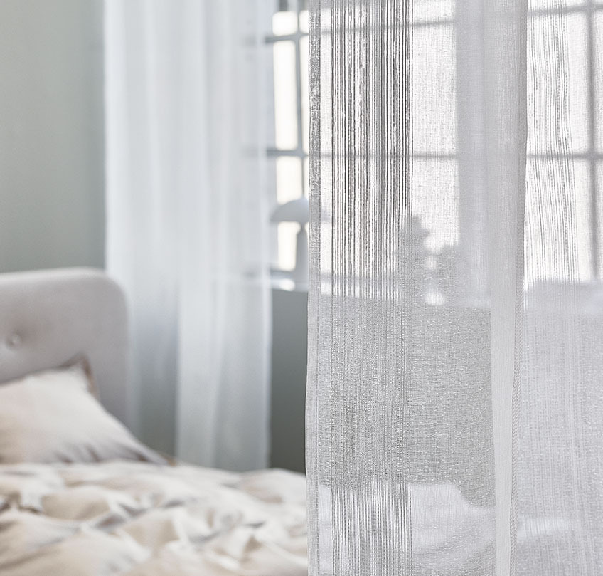 Cortinas brancas utilizadas para separar uma área de dormir de uma sala de estar 