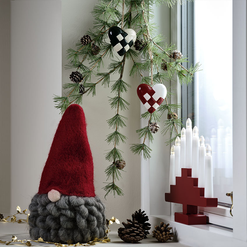 Duende de Natal escandinavo com barba cinzenta num parapeito de janela decorado