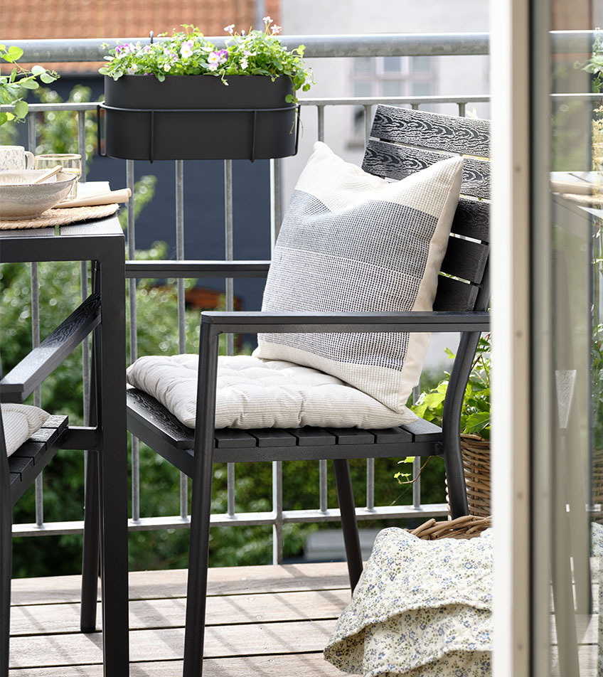 Cadeira de jardim empilhável preta com almofadas na varanda