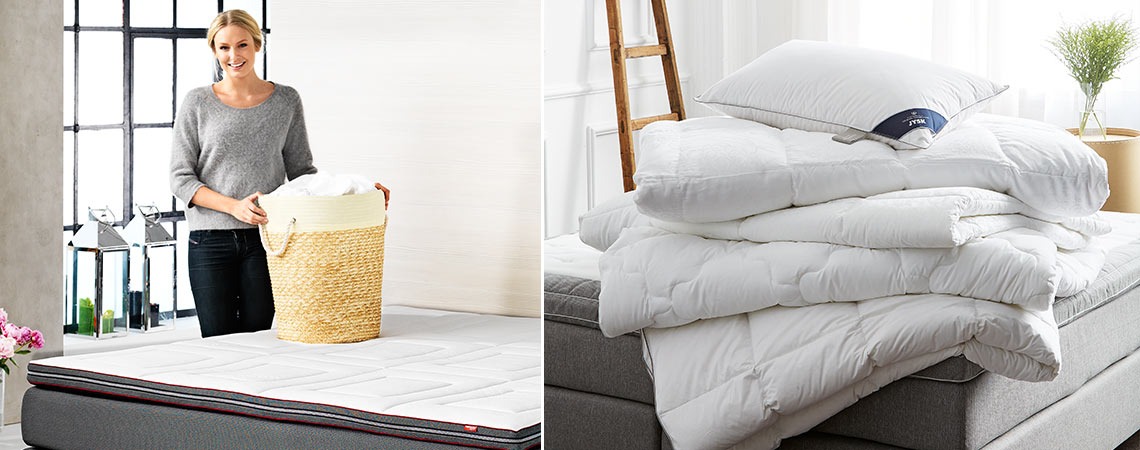 Edredões dobrados na cama com uma almofada e uma mulher com um cesto de roupa suja