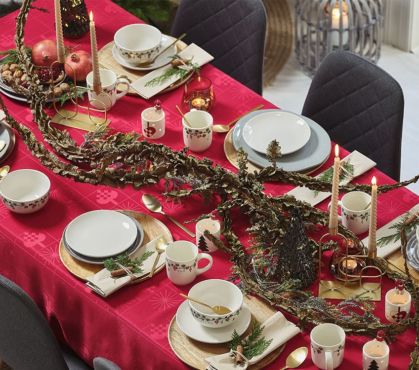 Mesa de jantar de Natal com talheres dourados e toalha em vermelho