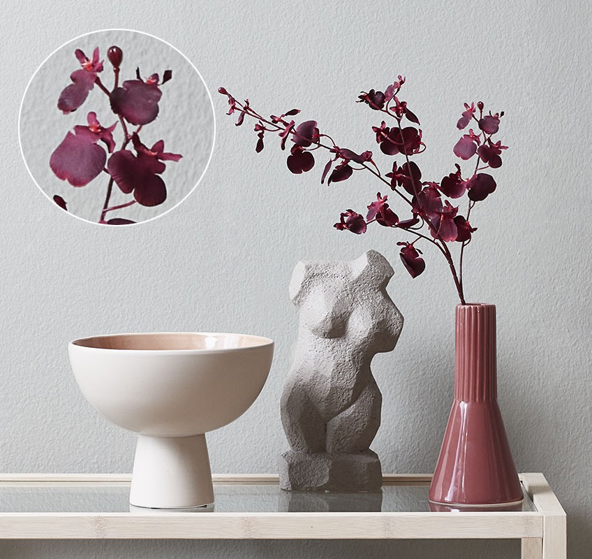 Pequeno vaso com flor de orquídea artificial e escultura de um corpo feminino