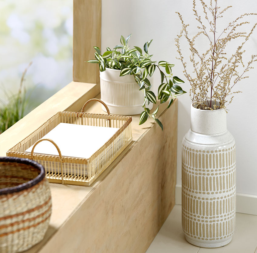 Tall vase beside windowsill with bamboo tray and white plant pot with artificial plant 